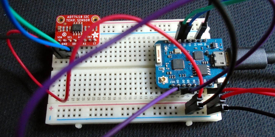 A hardware “breadboard” with a red sensor board (ADT7410 temperature sensor) and blue microcontroller (D1 Mini) attached by several colourful wires.